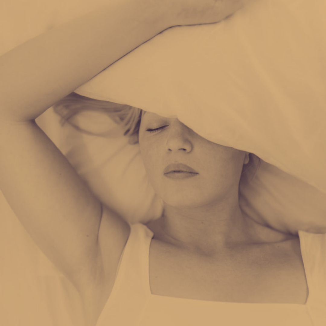 woman laying down in bed with a pillow partially covering her face